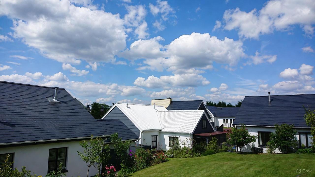 A high-angle view of a beige residential house featuring a newly installed silver r panel roofing system with a distinct ribbed metal profile.